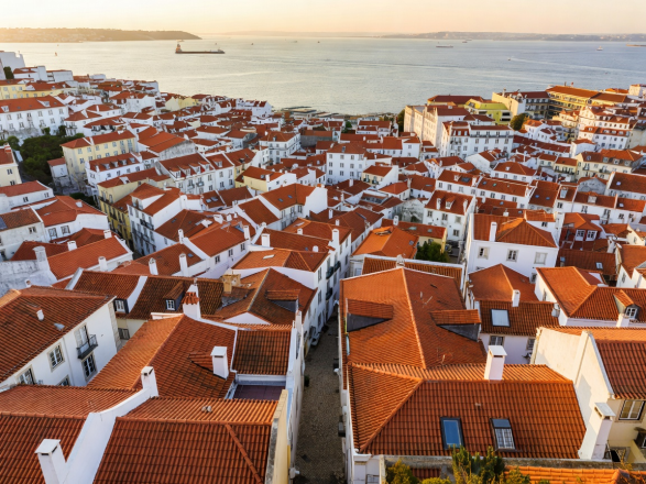 Panoramic view over terracotta rooftops of Lisbon Alfama down to Tagus estuary
